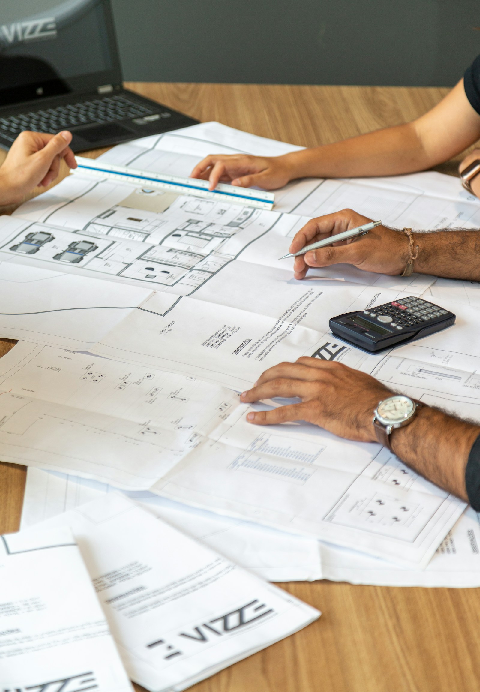 Professionals reviewing architectural plans, measurements and drawings at a table.